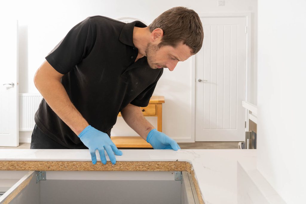 Guardian Ventures Trade Partner installing an Earthstone Glacier engineered stone worktop overlay in a modern kitchen using the Guardian Ventures installation system.